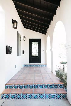 an entry way with blue and white tiles on the steps leading up to a black door