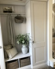 a white closet with some baskets and flowers on the shelf next to it is an entry way