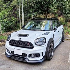 a white mini countryman parked in front of some trees