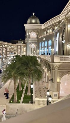 people are walking up and down the stairs in front of a large building at night