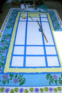 a table that has been decorated with blue and yellow squares, flowers, and scissors on it