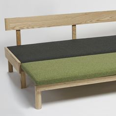 a bench made out of wood and green fabric on the backrest, against a white background