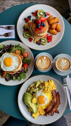 three plates with breakfast foods on them sitting on a table next to cups of coffee