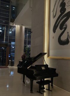 a grand piano sitting in the middle of a room next to a large painting on the wall