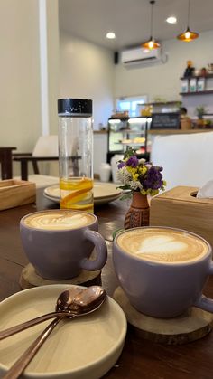 two cups of cappuccino sitting on top of a wooden table