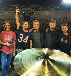 a group of men standing next to each other in front of a drum set on top of a stage