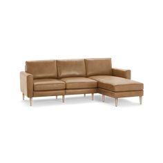 a tan leather sectional sofa with black legs and foot rest on an isolated white background