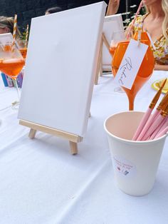 an easel and paintbrushes are sitting on a table next to a cup