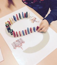 a child is making an art project with colored tape and magnets on the paper