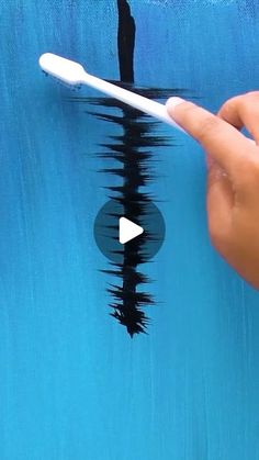 a hand holding a white toothbrush in front of a blue wall with black paint