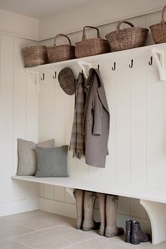 the coat rack is filled with coats and boots, along with two baskets on each shelf