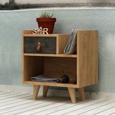 a wooden shelf sitting on top of a floor next to a potted plant and other items