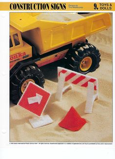 there are construction signs and toy trucks in the sand