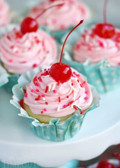 cupcakes with pink frosting, sprinkles and a cherry on top