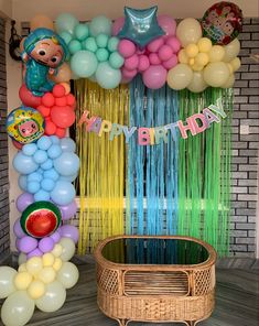 a birthday party with balloons and streamers on the wall in front of a basket