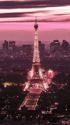 the eiffel tower lit up at night with pink sky in the back ground