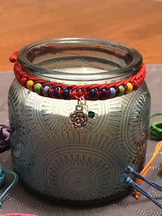 a glass jar sitting on top of a table filled with beads and other items next to it