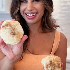 a woman holding up a piece of food in front of her face and smiling at the camera