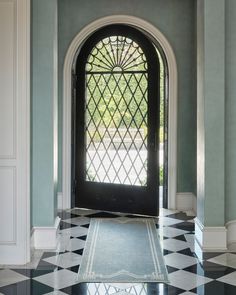 a black and white checkered floor in front of a door with an arched glass window