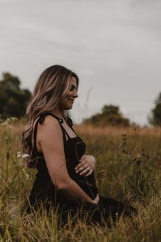 a woman sitting in the grass with her eyes closed and looking up into the sky