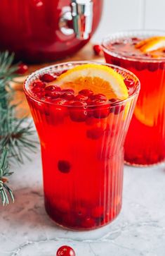 two glasses filled with cranberry punch and garnished with orange slices