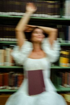 a blurry photo of a woman in a white dress holding her hands above her head