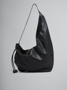 Large crossbody Hobo bag cut from nappa leather with a natural grain. The soft shape has an asymmetric silhouette with an adjustable drawstring strap with long laces that have two tonal leather baubles at the end. Zip closure. Black Smooth Grain Hobo Bag, Elegant Black Textured Leather Hobo Bag, Black Leather-lined Hobo Bag For Everyday Use, Luxury Black Textured Leather Hobo Bag, On-the-go Textured Leather Black Hobo Bag, Hobo Crossbody Bag, Flat Heel Boots, Lacing Sneakers, Boot Accessories