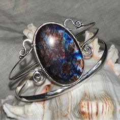 Artisan Designed & Handcrafted Aurora Borealis Blue Flash Labradorite Gemstone Handcrafted Cuff * Flashes Of Fire: Red, Blue, Purple And Gold * Circumference On Cuff Is 7.5-8.5” With 1” Adjustable Spacing * Hand Crafted 925 Sterling Silver Simulated The Flashes In The Aurora Borealis Labradorite Is A Member Of The Feldspar Family And Is Treasured For Its Remarkable Play Of Color. The Flashes Of Color, A Phenomenon Called Labradorescence. The Stone, Usually Gray-Green, Dark Gray, Black, Or Grayis Unique Labradorite Cuff Bracelet As Gift, Bohemian Oval Gemstone Cuff Bracelet, Adjustable Labradorite Cuff Bracelet As Gift, Unique Handmade Labradorite Cuff Bracelet, Unique Oval Gemstone Cuff Bracelet, Blue Gemstone Cuff Bracelet, Unique Blue Oval Cuff Bracelet, Bohemian Adjustable Cabochon Cuff Bracelet, Adjustable Bohemian Cuff Bracelet With Cabochon