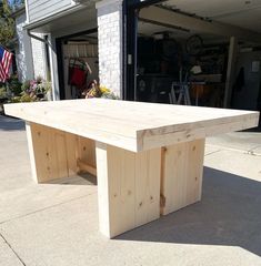 a large wooden table sitting on top of a cement floor in front of a garage