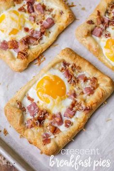 four square pizzas with eggs and ham on them sitting on a baking sheet, ready to be eaten