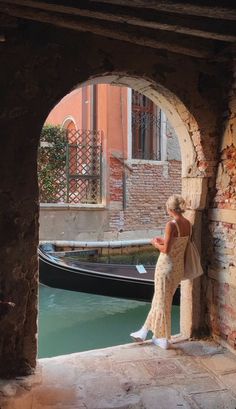 a woman standing on the edge of a bridge looking at her cell phone in front of a gondola