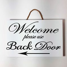 a welcome sign hanging on the wall with an arrow pointing to it's back door