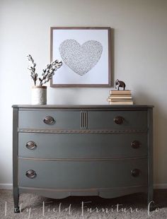 a dresser with two vases on top of it and a framed heart above it