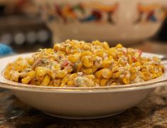 a white bowl filled with corn on top of a counter