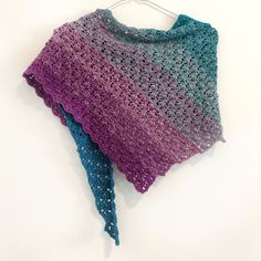 there is a crocheted shawl hanging on a hanger with two different colors