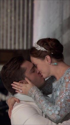 a man and woman kissing each other while wearing tiaras