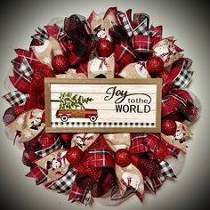 a christmas wreath with red, white and black plaid ribbon around it that says joy to the world