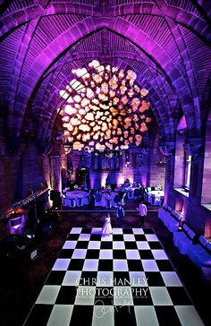 a large checkered floor is lit up with purple lights and chandeliers in the background