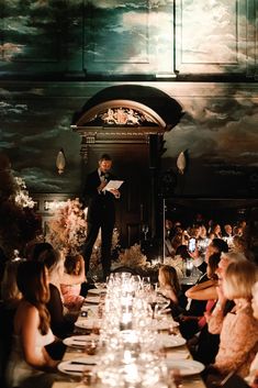 a man standing at the top of a table in front of a group of people