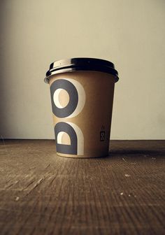 a single cup of coffee sitting on top of a wooden table next to a wall