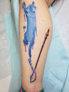 a person with a watercolor tattoo on their leg holding a wand and wearing green socks