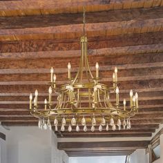 a chandelier hanging from the ceiling in a room with wood beams and exposed lighting