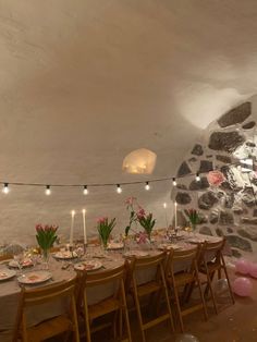 a table set up for a party with candles and flowers on the table in front of it