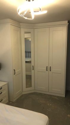 an empty bedroom with white closets and drawers