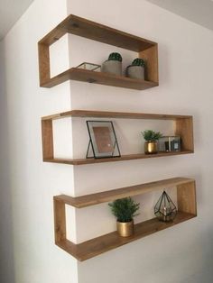 three wooden shelves on the wall with plants and other items in them, one is empty