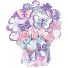 a vase filled with lots of butterflies on top of a white table topped with pink and purple flowers