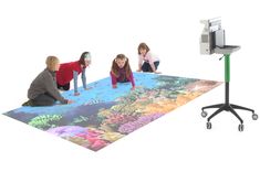 three children are playing with an underwater scene on a large floor mat while another child watches