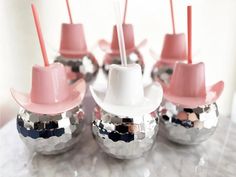 some silver balls with pink hats on them and straws sticking out of the tops