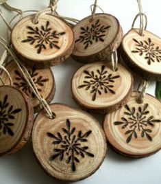 six wood slices with black snowflakes on them and some green leaves next to it