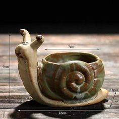 a ceramic snail planter sitting on top of a wooden table